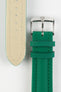 Close-up product photograph of a green textured leather watch strap displayed on a white background. The image shows both the top and underside of the strap, highlighting the fine embossed grain pattern, beige leather lining, matching green stitching, dual leather keepers, multiple sizing holes, and a polished stainless steel pin buckle engraved with the manufacturer's logo. The photograph showcases the strap's premium materials, craftsmanship, and classic tapered design.