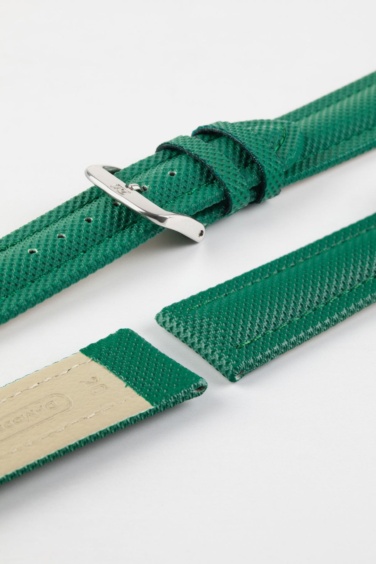 Close-up product photograph of a green textured leather watch strap displayed on a white background. The strap is shown in multiple sections, highlighting the embossed grain pattern, green leather keepers, polished stainless steel pin buckle, and the beige leather lining with embossed branding. The image showcases the strap's premium materials, refined texture, and classic tapered design.
