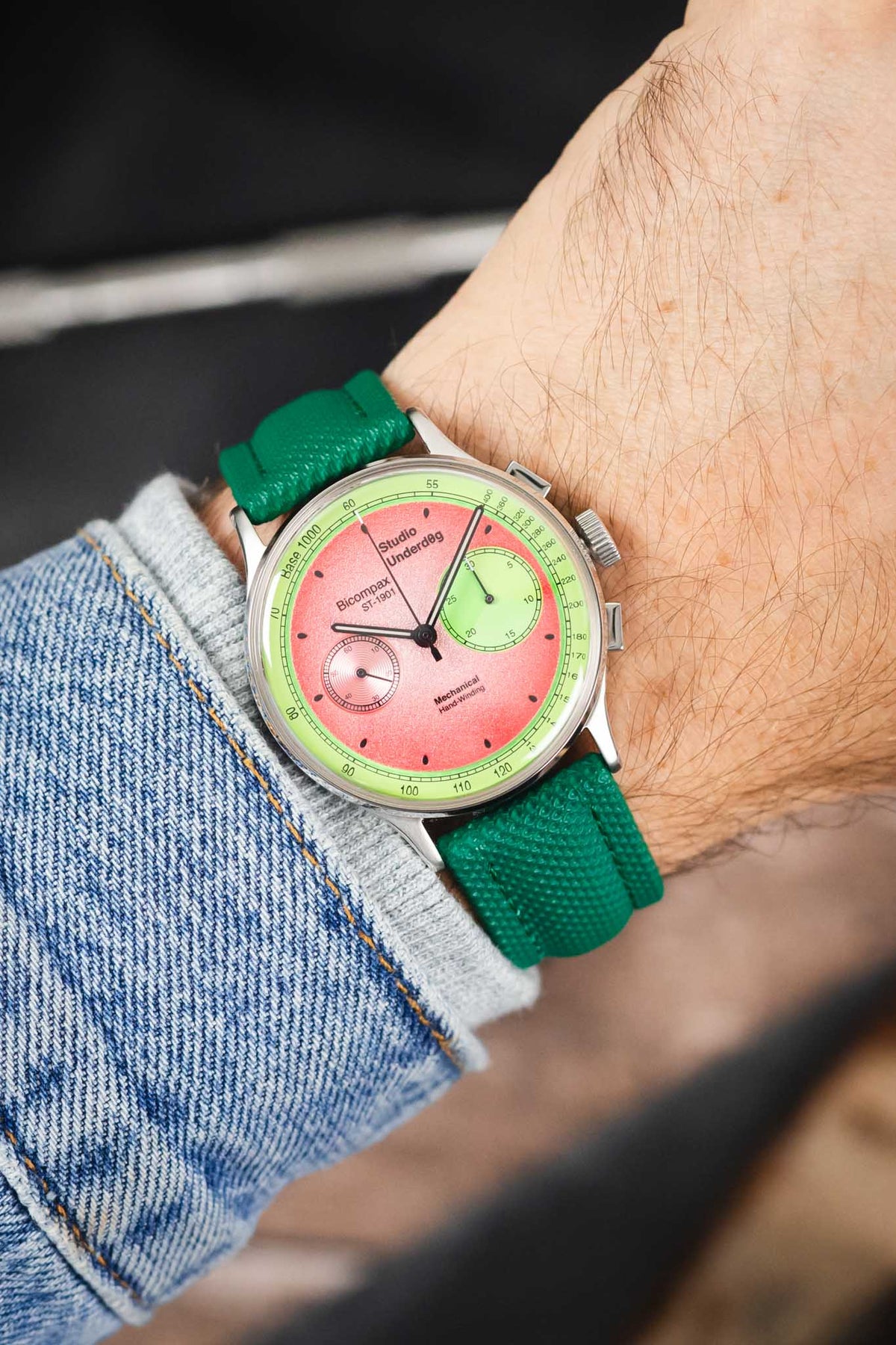 Studio Underd0g chronograph watch on a green textured leather strap, shown on wrist with a pink and green dial and stainless steel case.