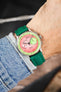 Studio Underd0g chronograph watch on a green textured leather strap, shown on wrist with a pink and green dial and stainless steel case.