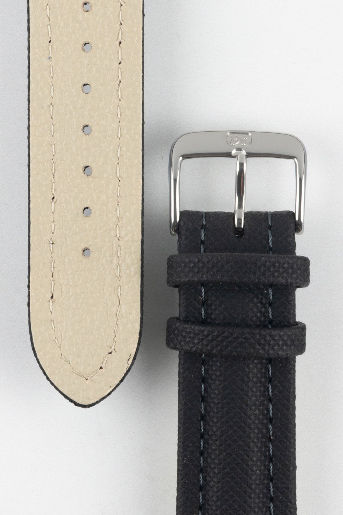 Close-up of a black Di-Modell Traveller leather watch strap on a white background, showing the textured leather finish, polished stainless steel buckle, matching black keepers, tonal stitching, beige leather-lined underside, multiple adjustment holes, and a tapered pointed tip.
