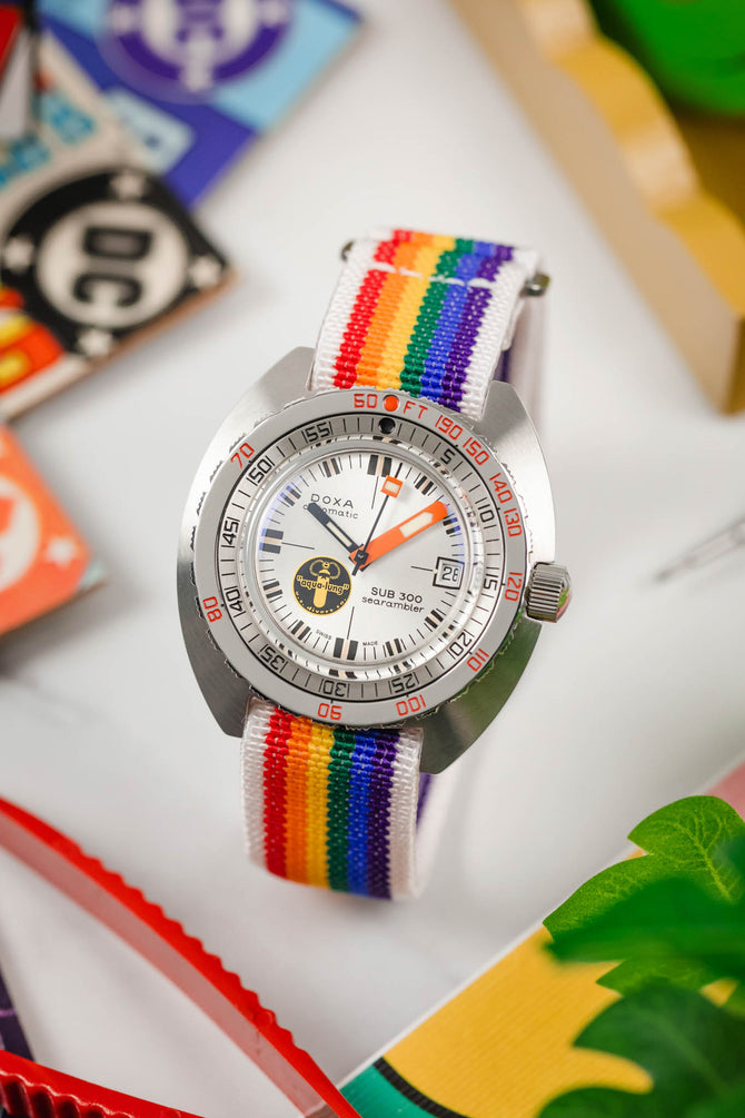 One-Piece rainbow pride watch strap with white stitching by Erikas Originals on a dive strap with orange hands