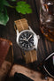Hamilton watch on a wooden table fitted to a brown parachute webbing watch strap with brushed stainless steel hardware