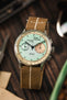 Panda dial watch on a wooden table fitted to a brown parachute webbing watch strap with brushed stainless steel hardware