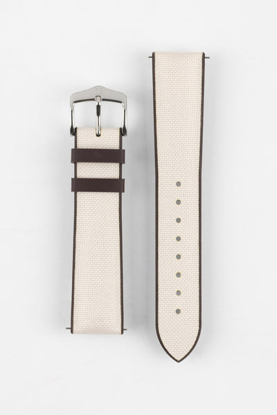 Beige textile-effect watch strap with a silver-tone buckle, displayed in two separate pieces on a white background. Features brown edges, a woven-look texture, and multiple adjustment holes.