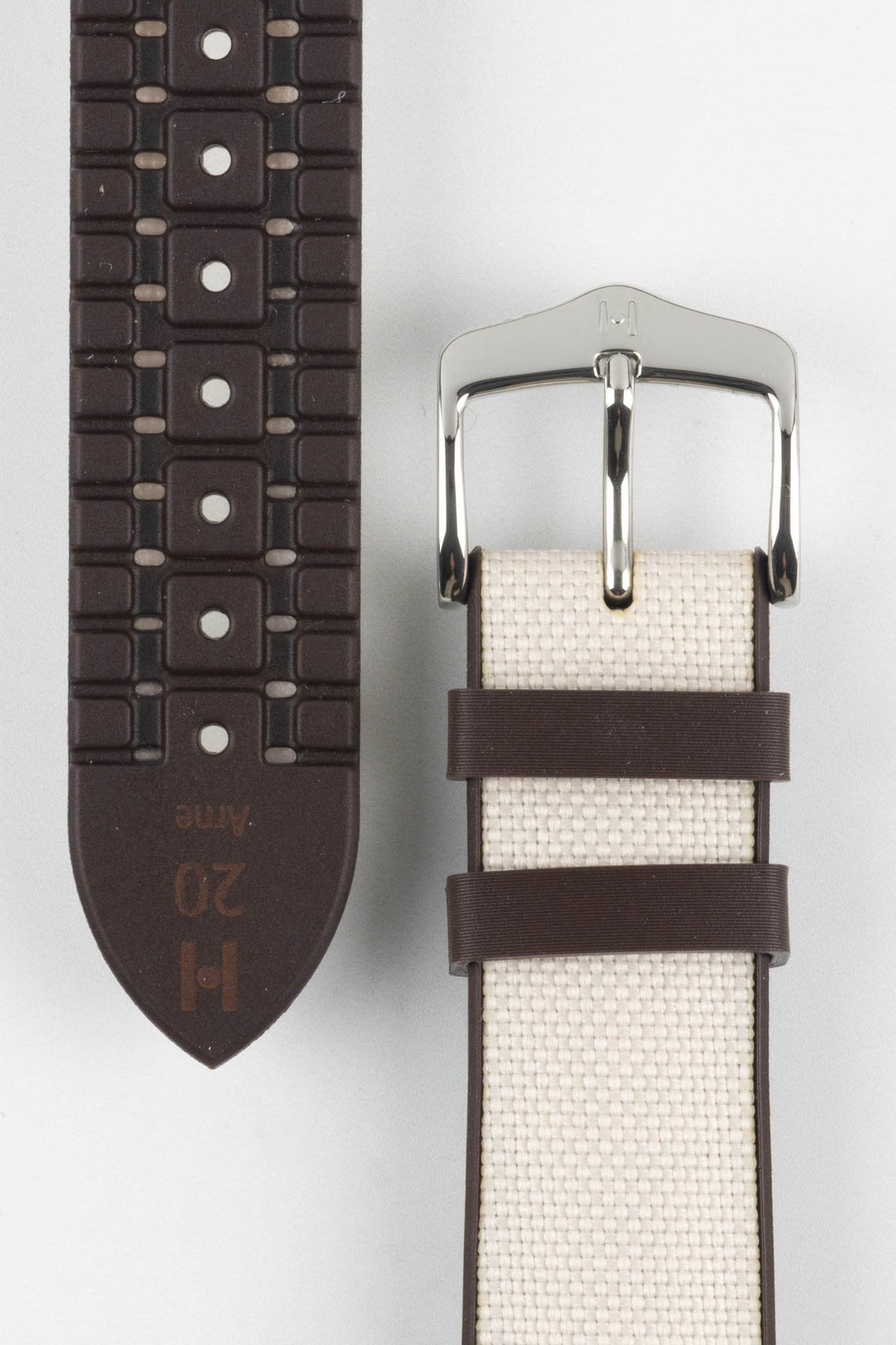 Beige textile-effect watch strap shown to display both the woven-look outer surface and brown rubber underside. Features a silver-tone buckle, brown edges, and a patterned rubber backing on a white background.