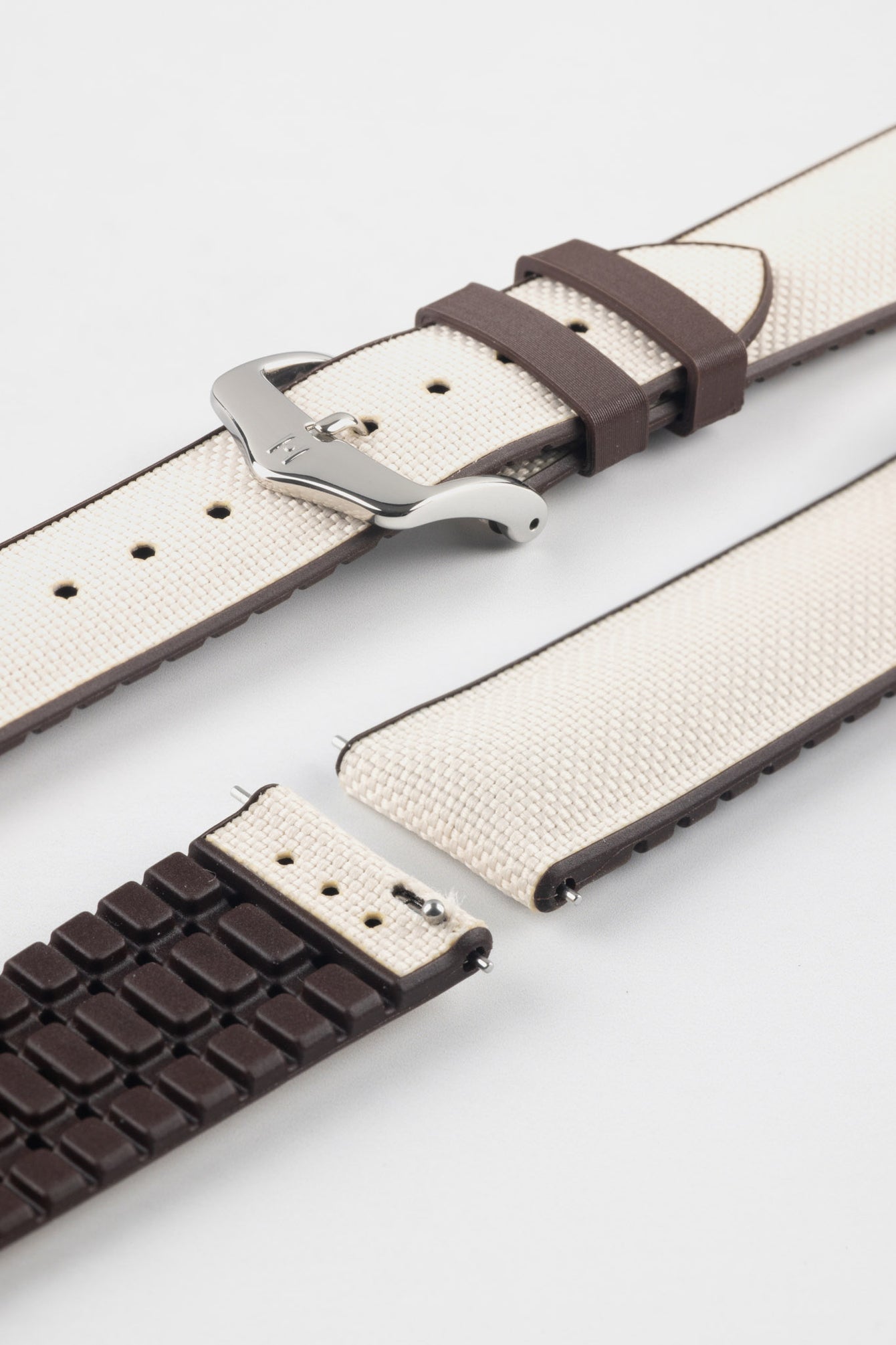 Beige textile-effect watch strap with brown rubber backing and a silver-tone buckle, shown in separate sections on a white background. Features a woven-look surface, brown edges, and a patterned rubber underside.