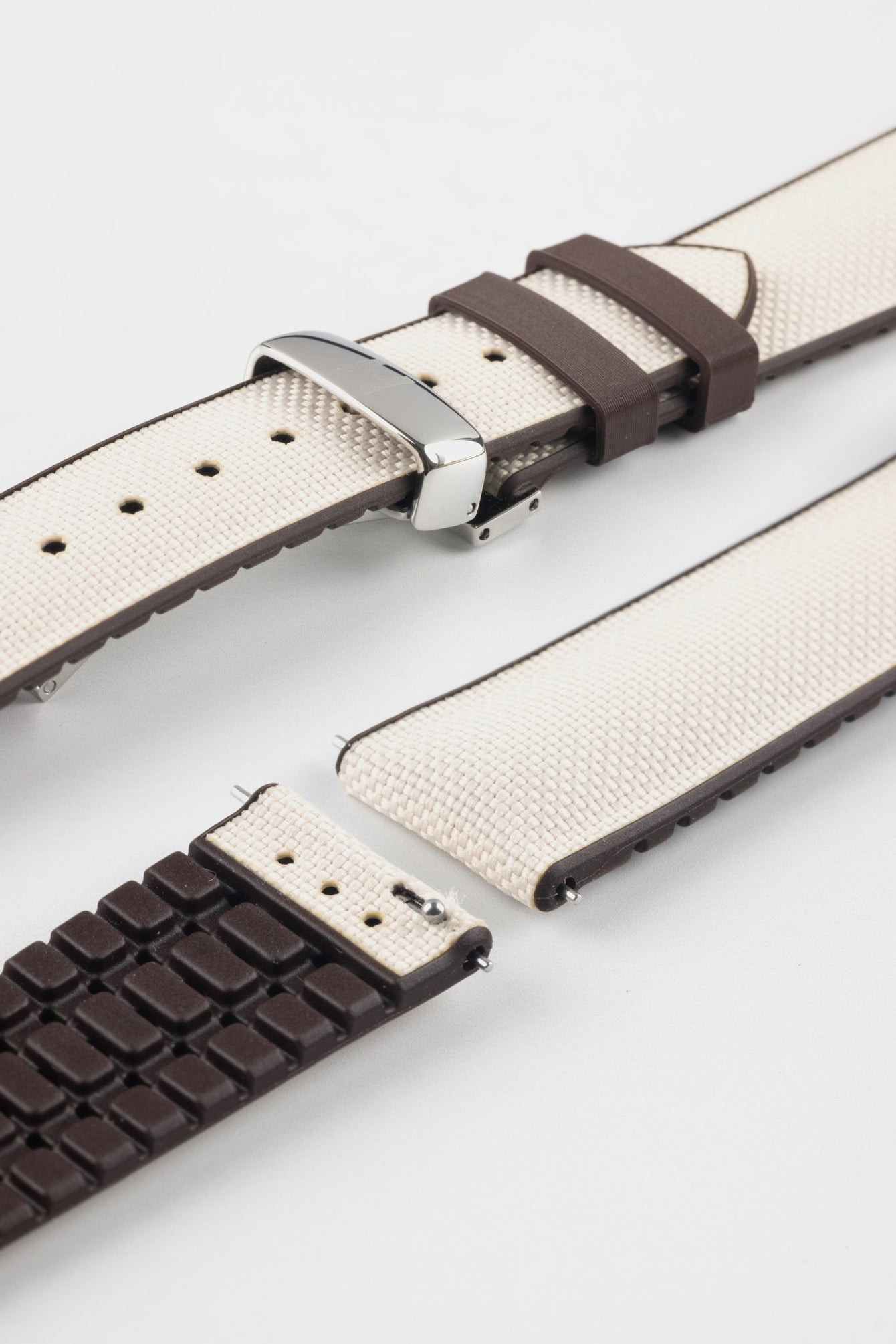 Light blue textile-effect watch strap with navy rubber backing and a black buckle, shown in separate sections on a white background. Features a textured woven-look surface, navy edges, and a patterned rubber underside.