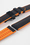 Black textile-effect watch strap with bright orange rubber backing and a black deployment clasp, shown in separate sections on a white background. Features a textured woven-look surface, orange edges, and a patterned rubber underside.