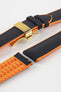 Black textile-effect watch strap with bright orange rubber backing and a gold-tone deployment clasp, shown in separate sections on a white background. Features a textured woven-look surface, orange edges, and a patterned rubber underside.