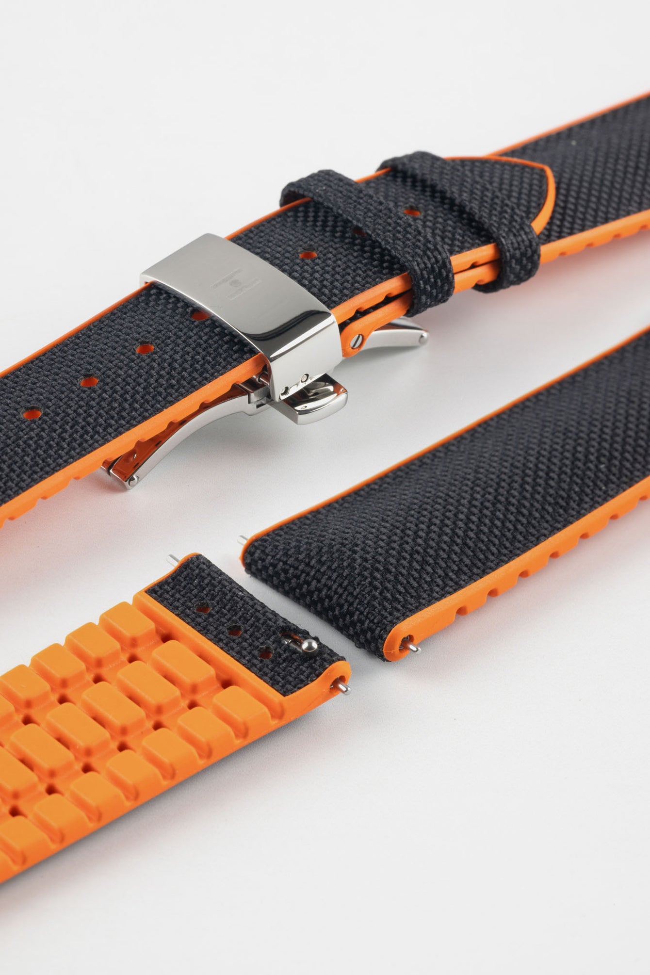 Black textile-effect watch strap with bright orange rubber backing and a silver-tone deployment clasp, shown in separate sections on a white background. Features a textured woven-look surface, orange edges, and a patterned rubber underside.