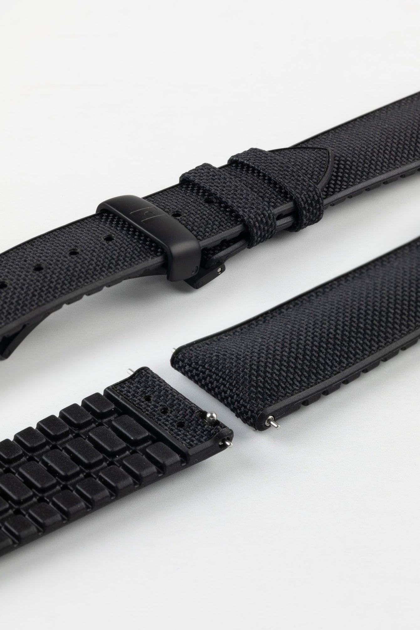 A detailed, slightly angled shot of a black Hirsch Arne Performance Watch Strap, laid in two pieces on a white background, highlighting its woven black upper, black ribbed underside, and a black clasp.