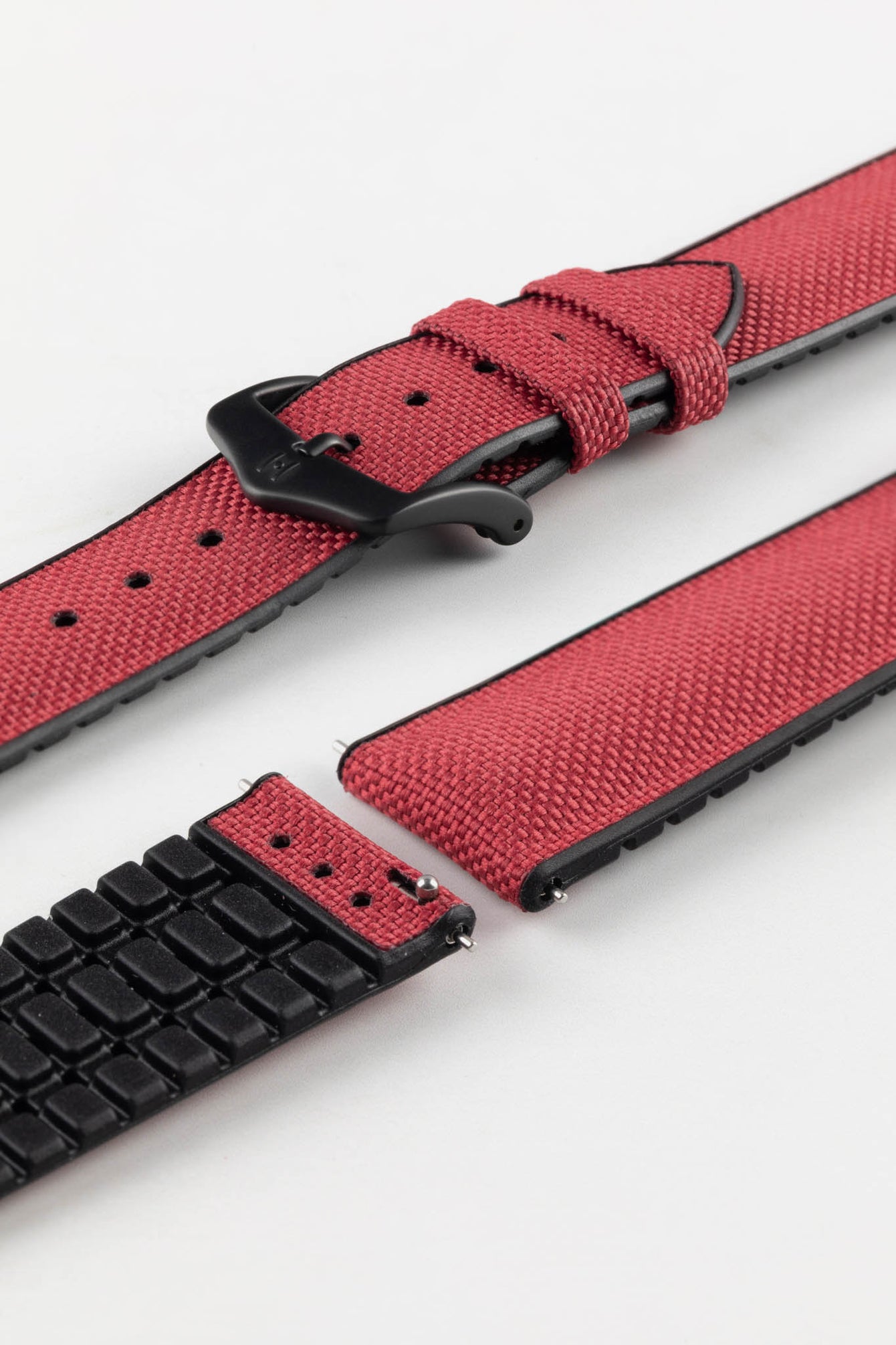A burgundy Hirsch Arne Animal-Free Sailcloth Effect Performance Watch Strap is displayed on a white background, showcasing the strap's full length and a matte black pin buckle. The textured sailcloth-like material of the strap is also clearly visible.