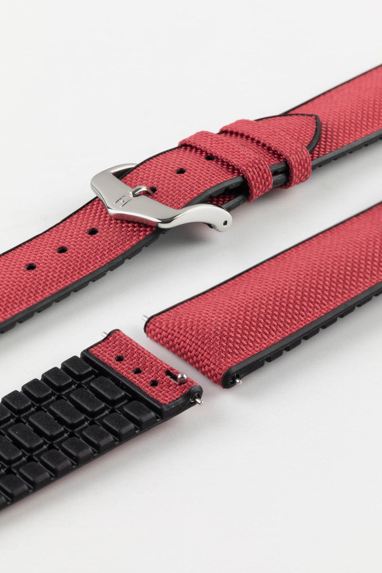 A burgundy Hirsch Arne Animal-Free Sailcloth Effect Performance Watch Strap is displayed on a white background, showcasing the strap's full length and a polished steel pin buckle. The textured sailcloth-like material of the strap is also clearly visible, along with the black rubberized underside.