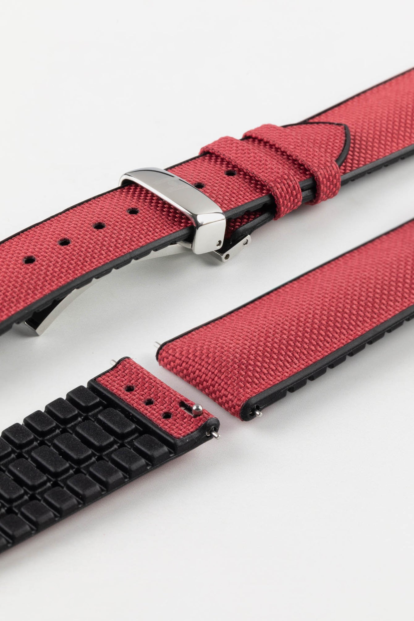 A burgundy Hirsch Arne Animal-Free Sailcloth Effect Performance Watch Strap is displayed on a white background, showcasing the strap's full length and a polished silver deployment clasp. The textured sailcloth-like material of the strap is also clearly visible, along with the black rubberized underside.