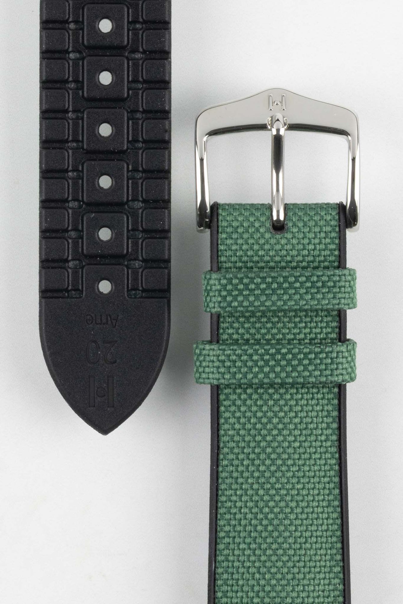 A detailed close-up of a dark green Hirsch Arne Animal-Free Sailcloth Effect Performance watch strap laid out on a white surface. The image clearly shows the textured green fabric on the top, the black rubberized underside with ventilation channels and the word "Arne" and "20" embossed, and the polished silver buckle.
