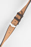Golden brown textile-effect watch strap with a silver-tone buckle, shown fastened on a white background. Features brown edges, a woven-look texture, and a brown rubber backing.
