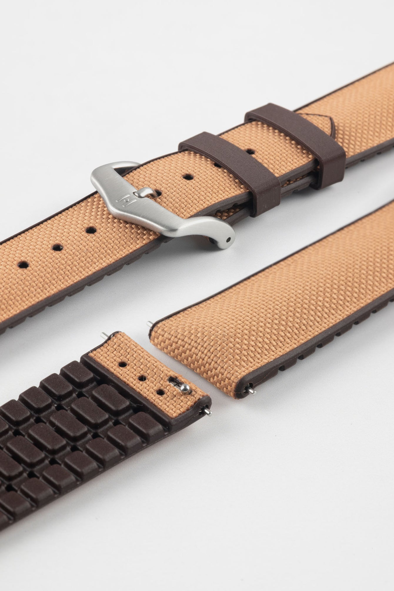 Golden brown textile-effect watch strap with brown rubber backing and a brushed silver-tone buckle, shown in separate sections on a white background. Features a woven-look surface, brown edges, and a patterned rubber underside.