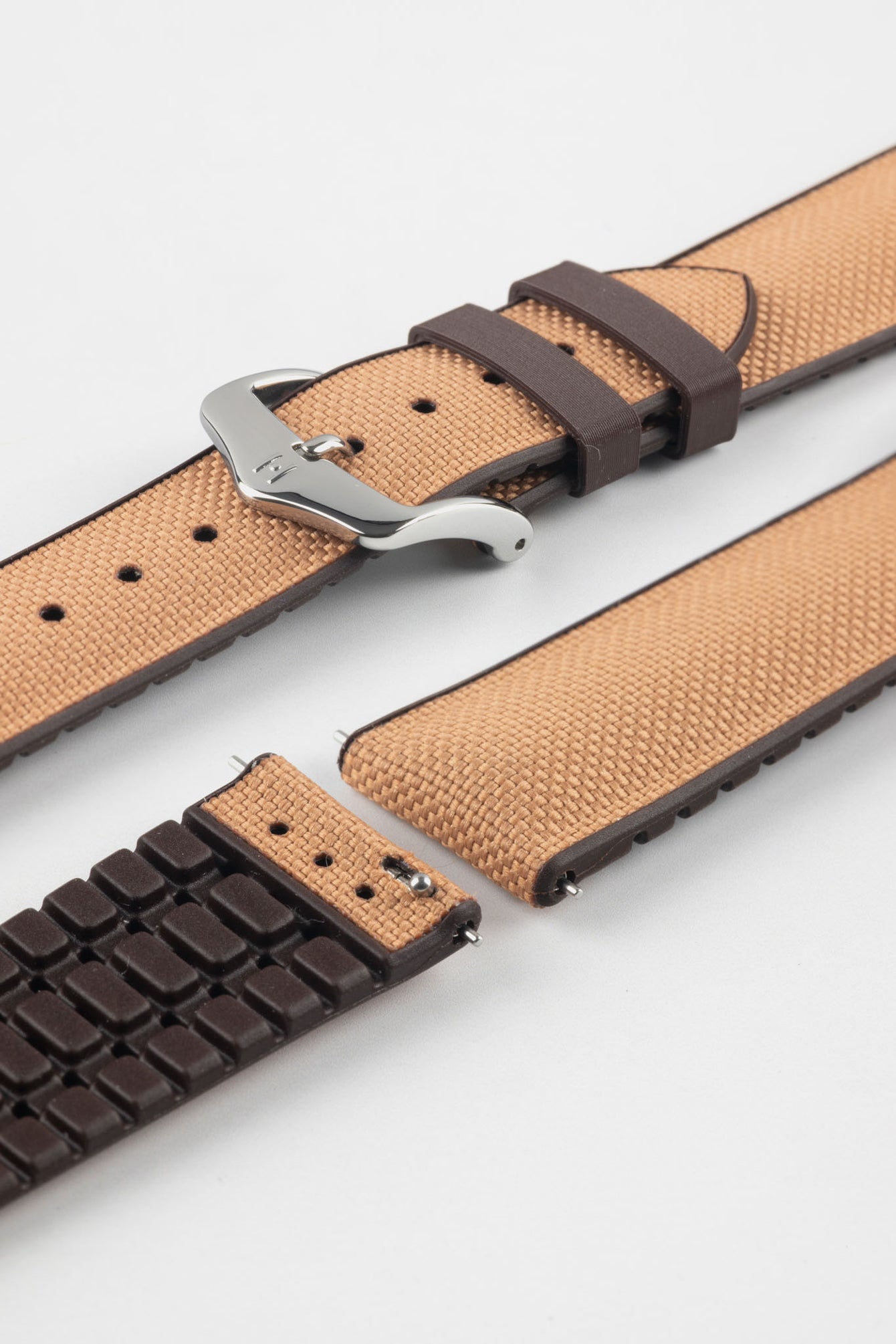 Golden brown textile-effect watch strap with brown rubber backing and a silver-tone buckle, shown in separate sections on a white background. Features a woven-look surface, brown edges, and a patterned rubber underside.