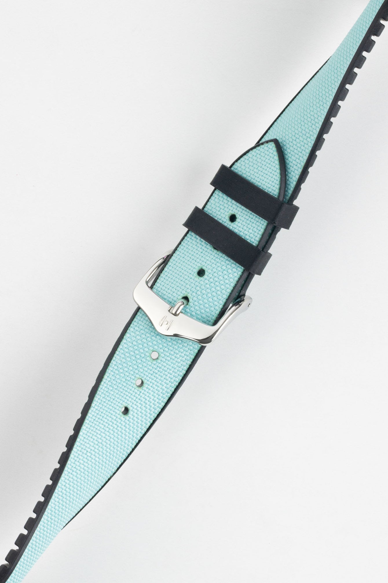 Ice blue textile-effect watch strap with a silver-tone buckle, shown fastened on a white background. Features black edges, a woven-look texture, and a black rubber backing.