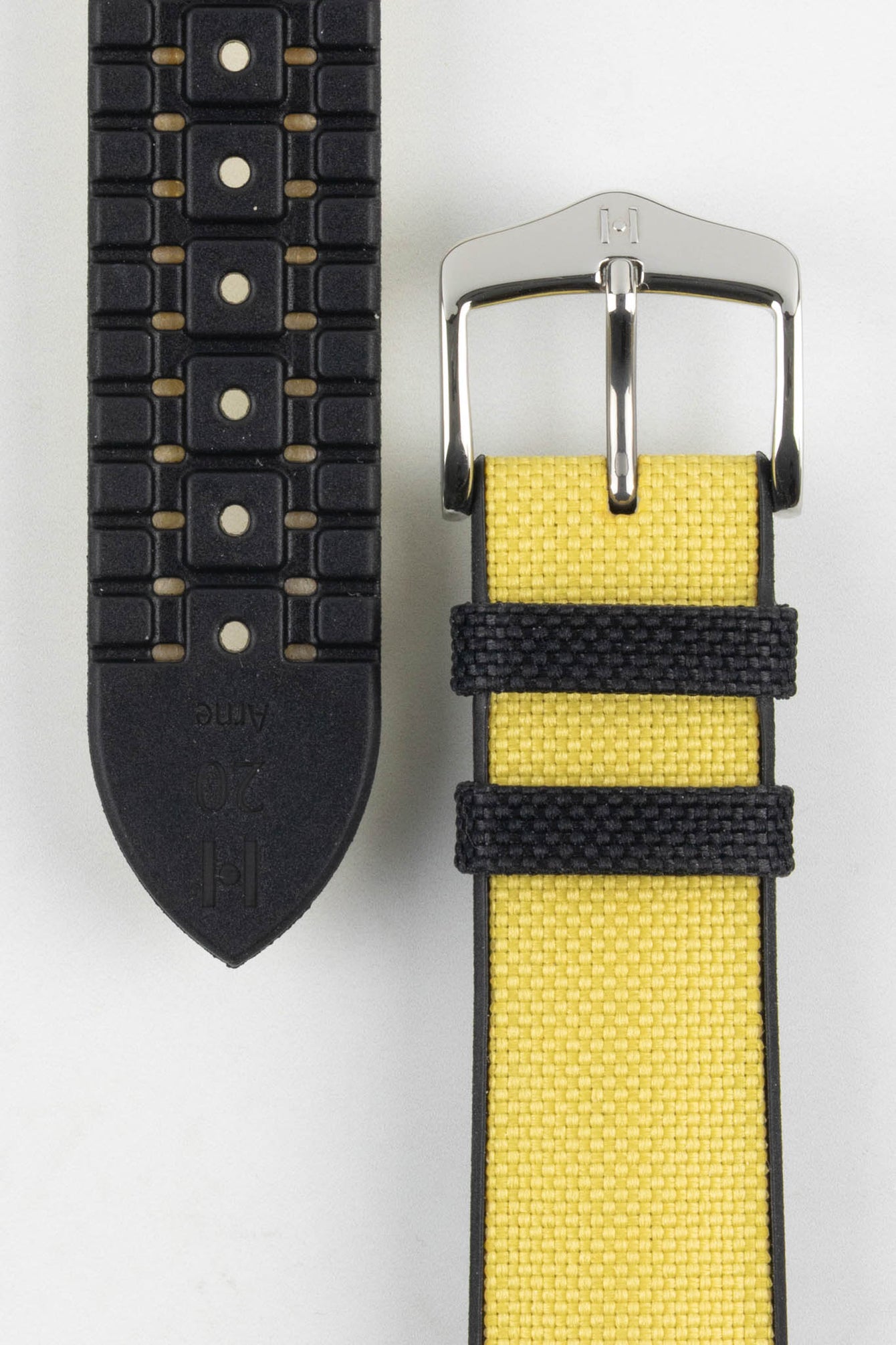 A detailed close-up of a yellow Hirsch Arne Animal-Free Sailcloth Effect Performance watch strap laid out on a white surface. The image clearly shows the textured yellow fabric on the top with black keepers, the black rubberized underside with ventilation channels and the word "Arne" and "20" embossed, and the polished silver buckle.