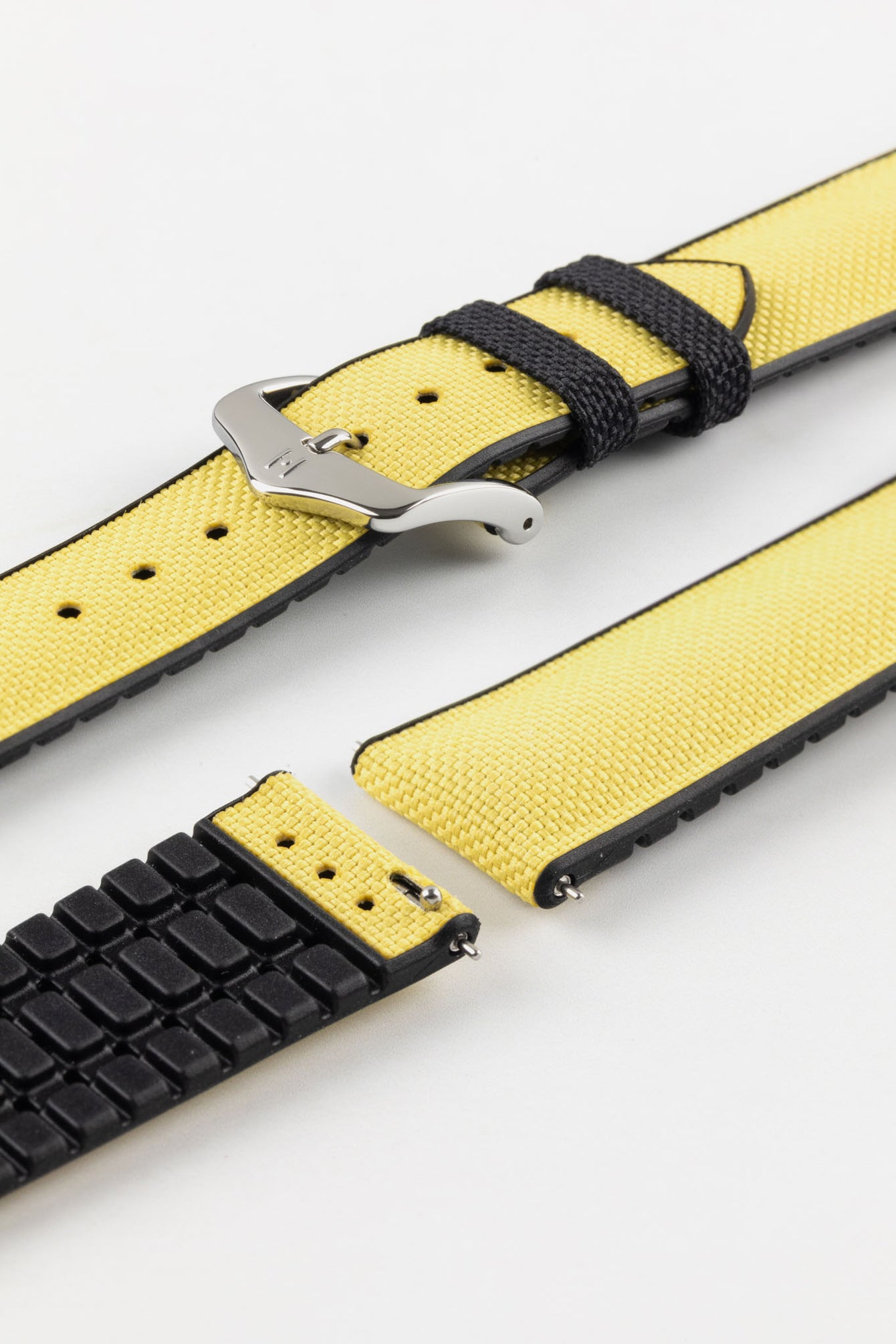 Detailed view of a Hirsch Arne watch strap, featuring a bright yellow sailcloth-textured surface with black leather accents and a polished silver pin buckle. The strap is partially detached, showing the pin mechanism.