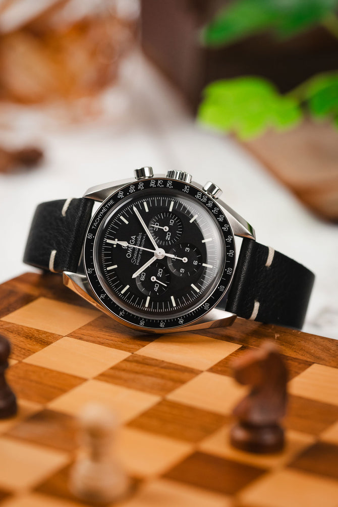Omega Speedmaster with black vintage style two-stitch strap.