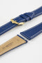 Close-up product image of a blue textured leather watch strap with white contrast stitching, displayed against a white background, featuring a polished gold-tone pin buckle and two keepers, alongside separate strap sections with exposed spring bars and a beige underside stamped with partial text “20 HIRSCH Bologna.”