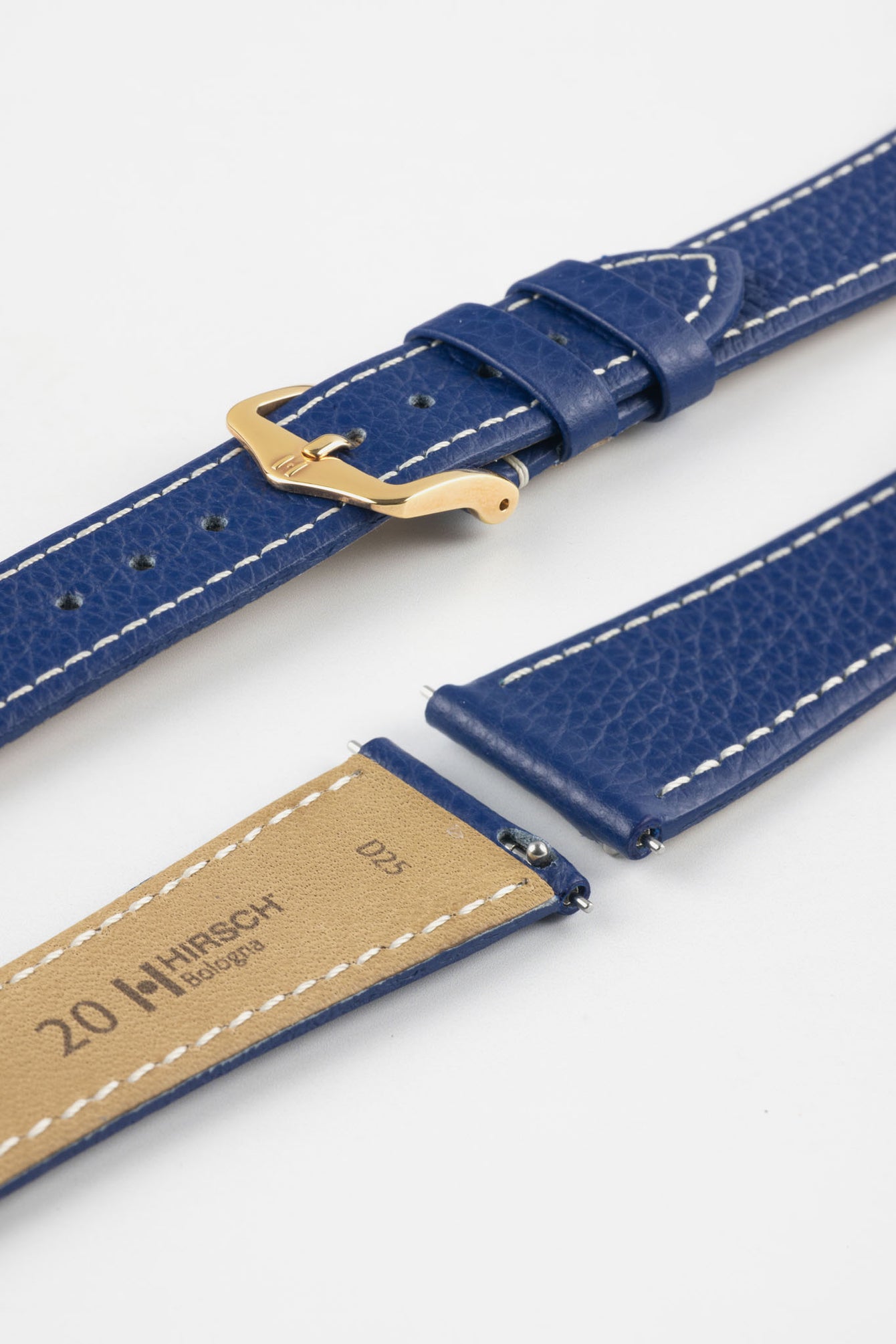 Close-up product image of a blue textured leather watch strap with white contrast stitching, displayed against a white background, featuring a polished gold-tone pin buckle and two keepers, alongside separate strap sections with exposed spring bars and a beige underside stamped with partial text “20 HIRSCH Bologna.”