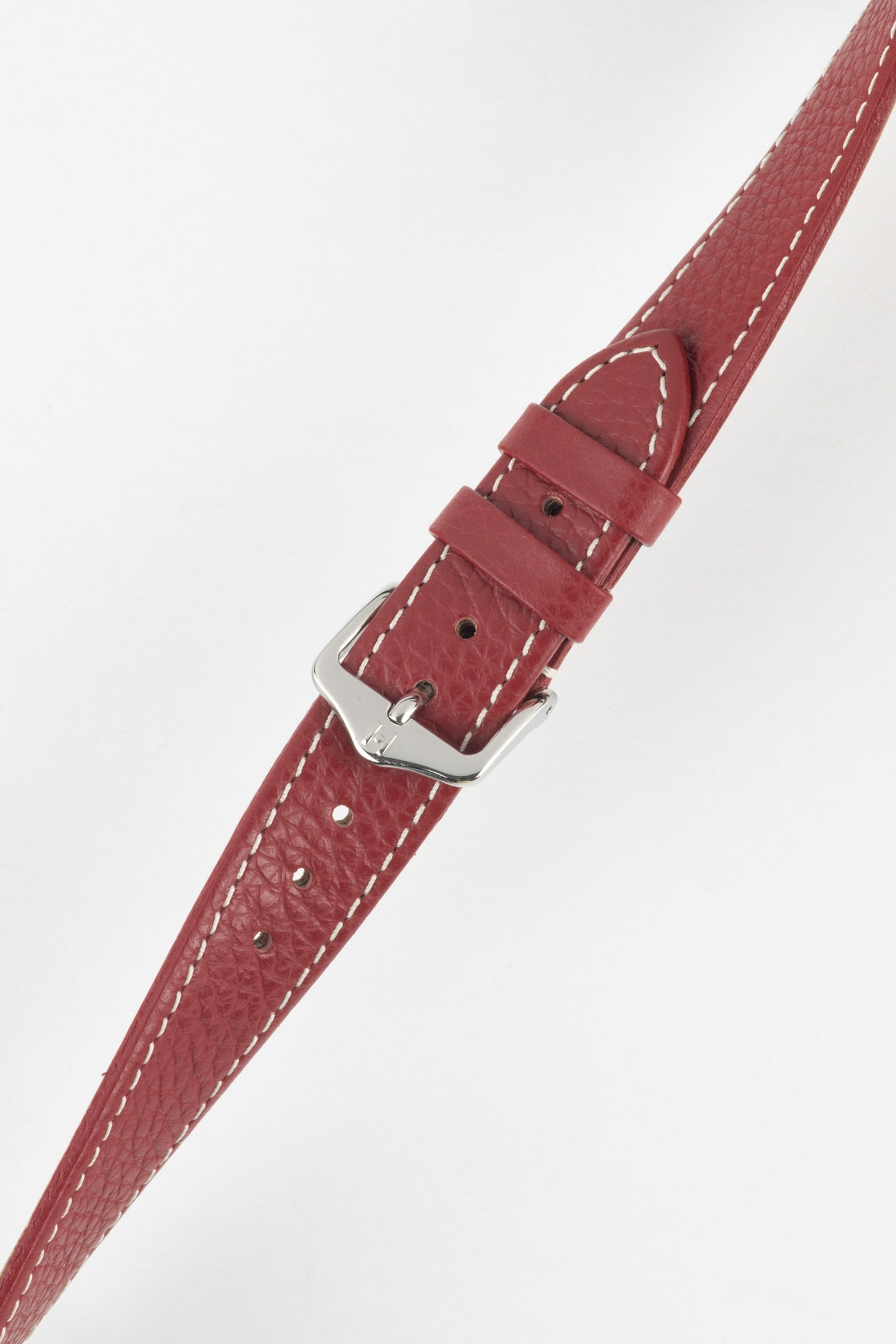 Close-up of a red textured leather watch strap with white contrast stitching, featuring a polished silver-tone pin buckle and two keepers, with visible adjustment holes and a softly grained finish against a white background.