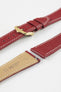 Close-up product image of a red textured leather watch strap with white contrast stitching, displayed against a white background, featuring a polished gold-tone pin buckle with two keepers, alongside separate strap sections with exposed spring bars and a beige underside stamped with partial text “20 HIRSCH.”