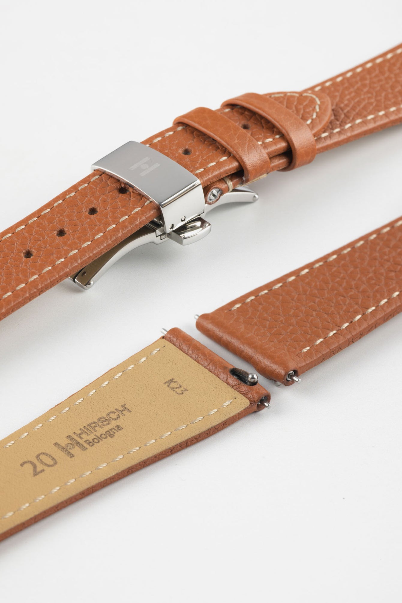 Gold brown leather watch strap with a stainless steel deployant clasp, shown with a beige leather underside and white contrast stitching.