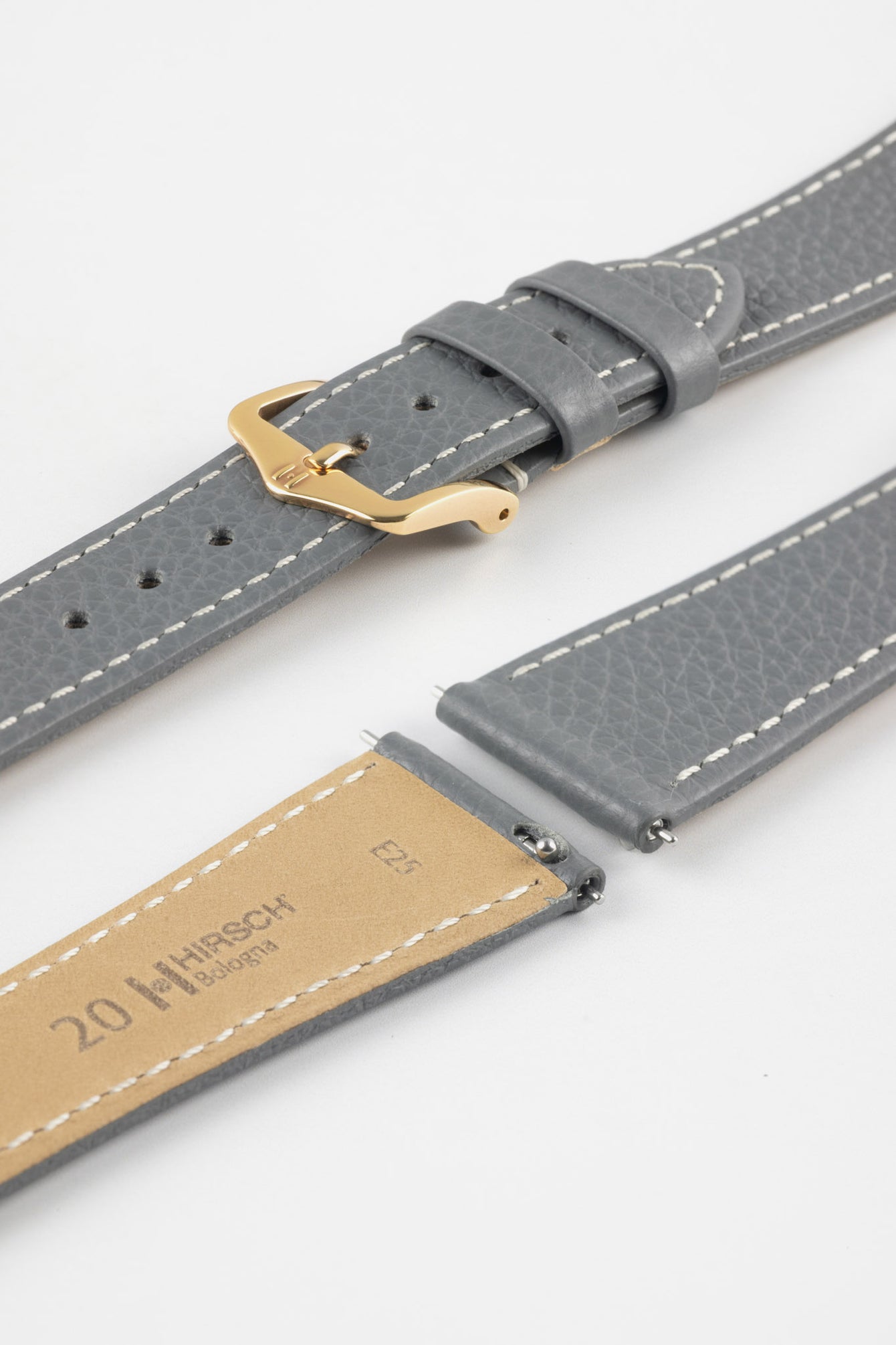 
Close-up product image of a grey textured leather watch strap with white contrast stitching, displayed against a white background, featuring a polished rose gold-tone pin buckle and two keepers, alongside separate strap sections with exposed spring bars and a beige underside stamped with partial text “20 HIRSCH Bologna.”