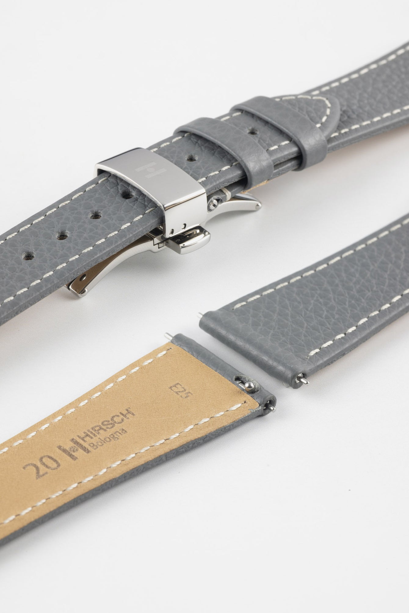 Grey leather watch strap with white stitching and a silver deployment clasp, shown alongside additional strap pieces and a tan underside stamped “HIRSCH Bologna” and “20.”