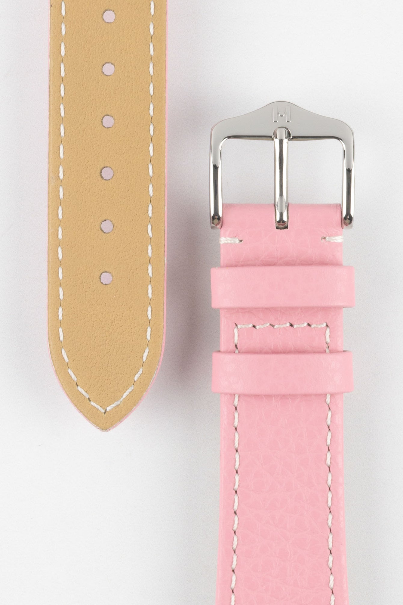 Close-up product image of a pink textured leather watch strap against a white background, showing the underside with multiple adjustment holes and beige lining on one section, and the other with a polished silver-tone pin buckle and two keepers, highlighting the white contrast stitching and fine grain texture.
