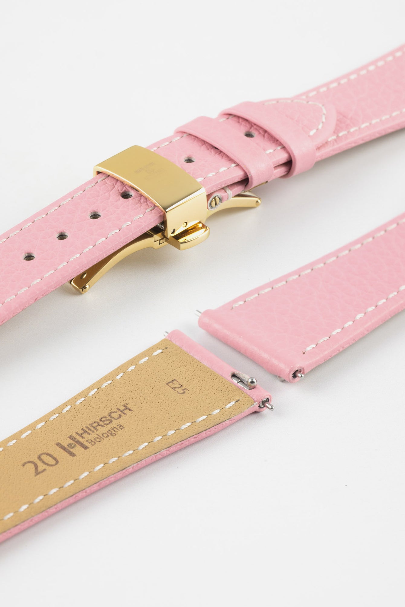 Close-up of a pink leather watch strap with white stitching and a gold-tone butterfly clasp, displayed open alongside separate strap pieces with exposed spring bars and a tan underside stamped with Hirsch Bologna branding, set against a clean white background.