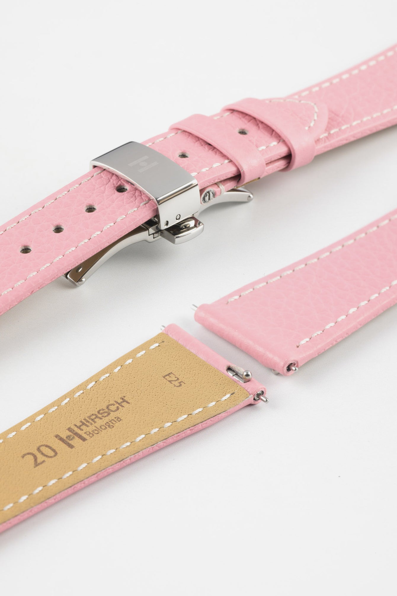 Close-up of a pink leather watch strap with white stitching and a polished silver butterfly clasp, displayed open alongside detached strap pieces with visible spring bars and a tan underside stamped with Hirsch branding, set against a plain white background.