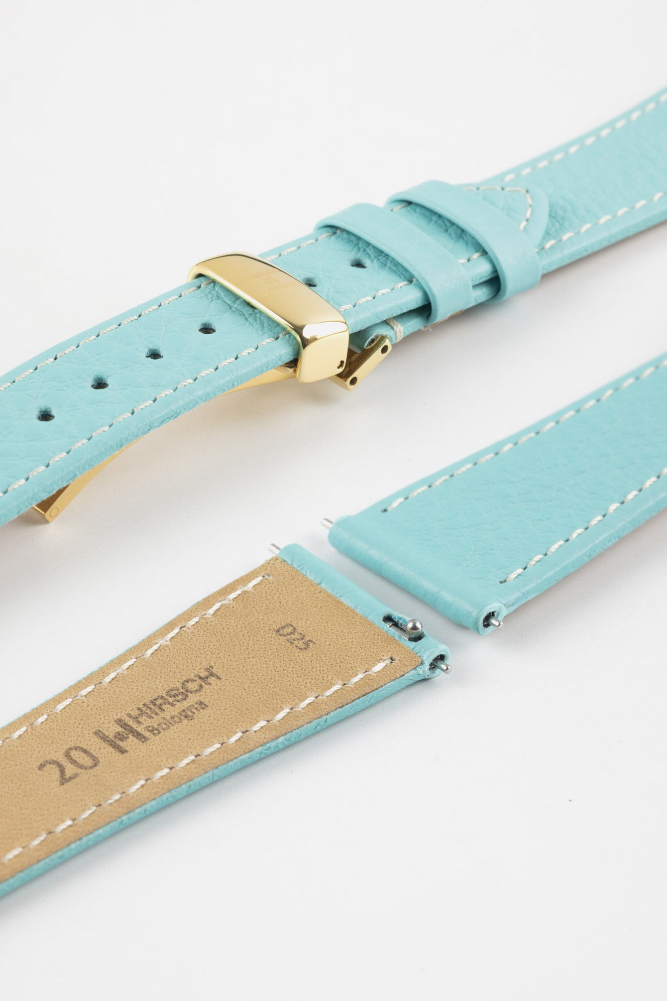 Close-up product image of a light turquoise-blue textured leather watch strap with white contrast stitching, displayed on a white background, featuring a polished gold-tone folding clasp and two keepers, alongside separate strap sections with exposed spring bars and a beige underside stamped with partial text “20 HIRSCH Bologna.”