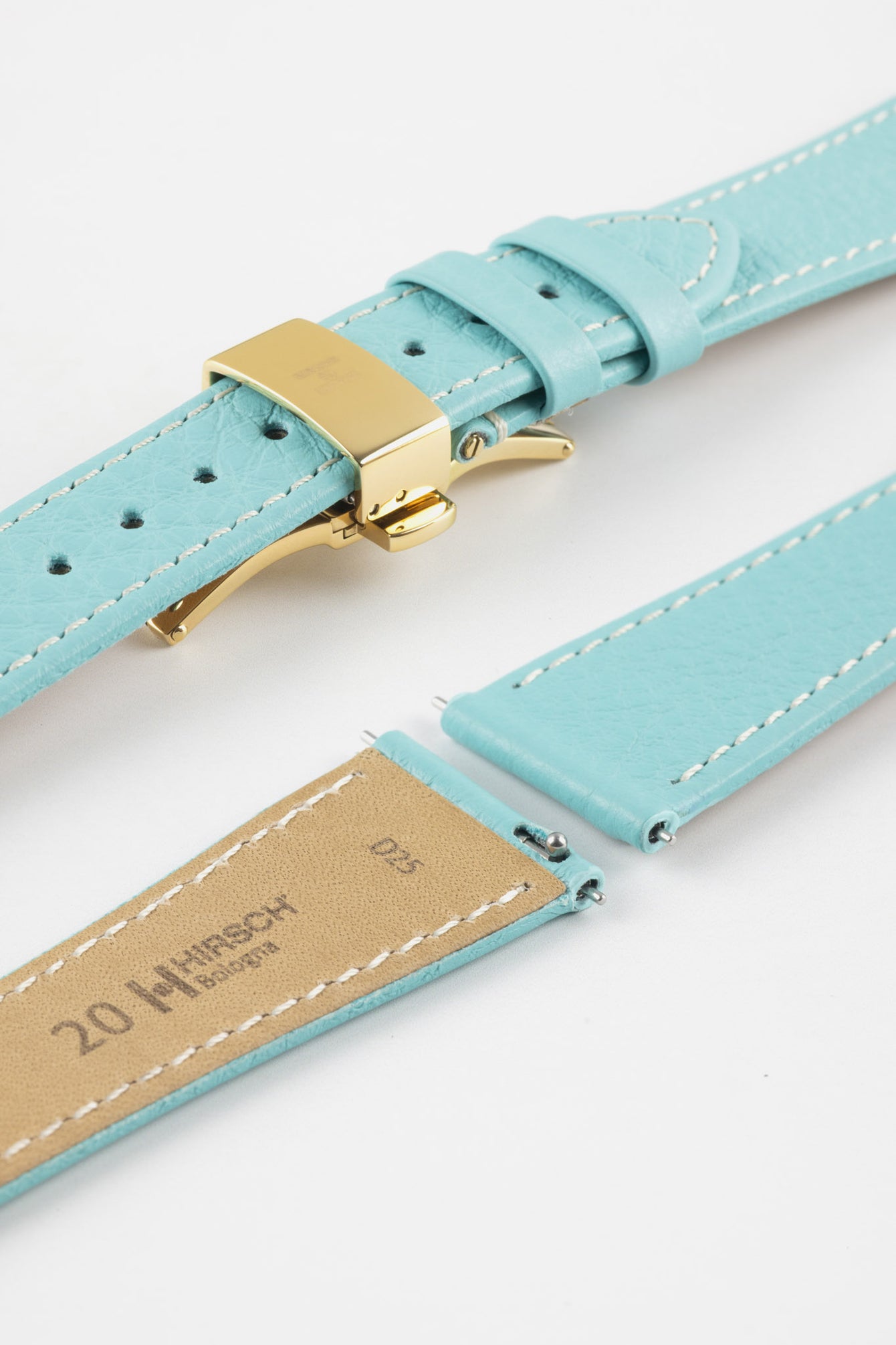 Close-up of a turquoise leather watch strap with white stitching and a gold-tone butterfly clasp, shown open alongside detached strap pieces with exposed spring bars on a plain white background.