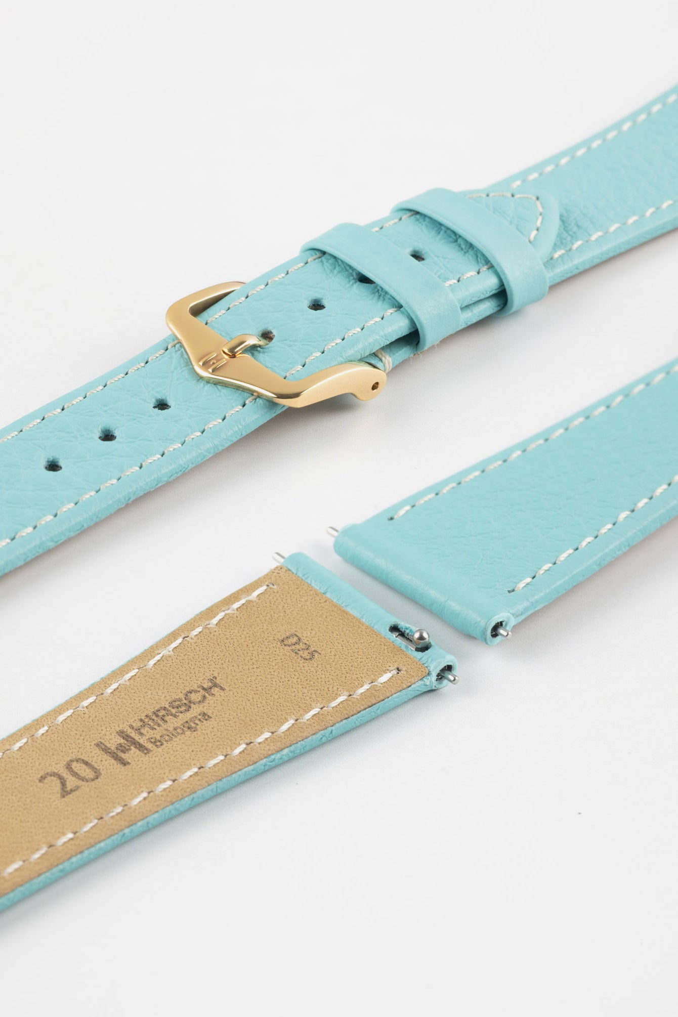 Close-up product image of a light turquoise-blue textured leather watch strap with white contrast stitching, displayed against a white background, featuring a polished gold-tone pin buckle and two keepers, alongside separate strap sections with exposed spring bars and a beige underside stamped with partial text “20 HIRSCH Bologna.”