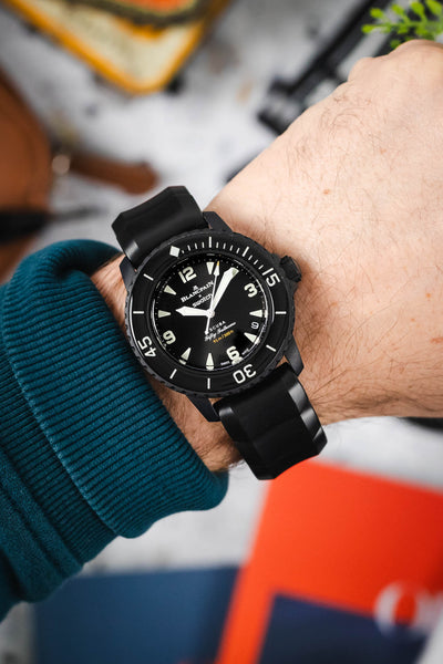 A mans hand wearing a Blancpain X Swatch Fifty Fathoms Watch. The watch is fitted to a chunky rubber Hirsch Extreme Watch Strap in Black.