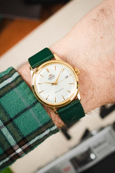 Wrist shot of a Hirsch Giffone dark green leather strap fitted to a gold Orient Bambino automatic watch.