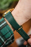 Side view of a Hirsch Giffone dark green textured leather strap on a gold Orient Bambino watch, worn on wrist.