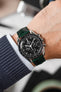 Black Omega Speedmaster Moonwatch fitted with Hirsch London dark green leather watch strap worn on wrist