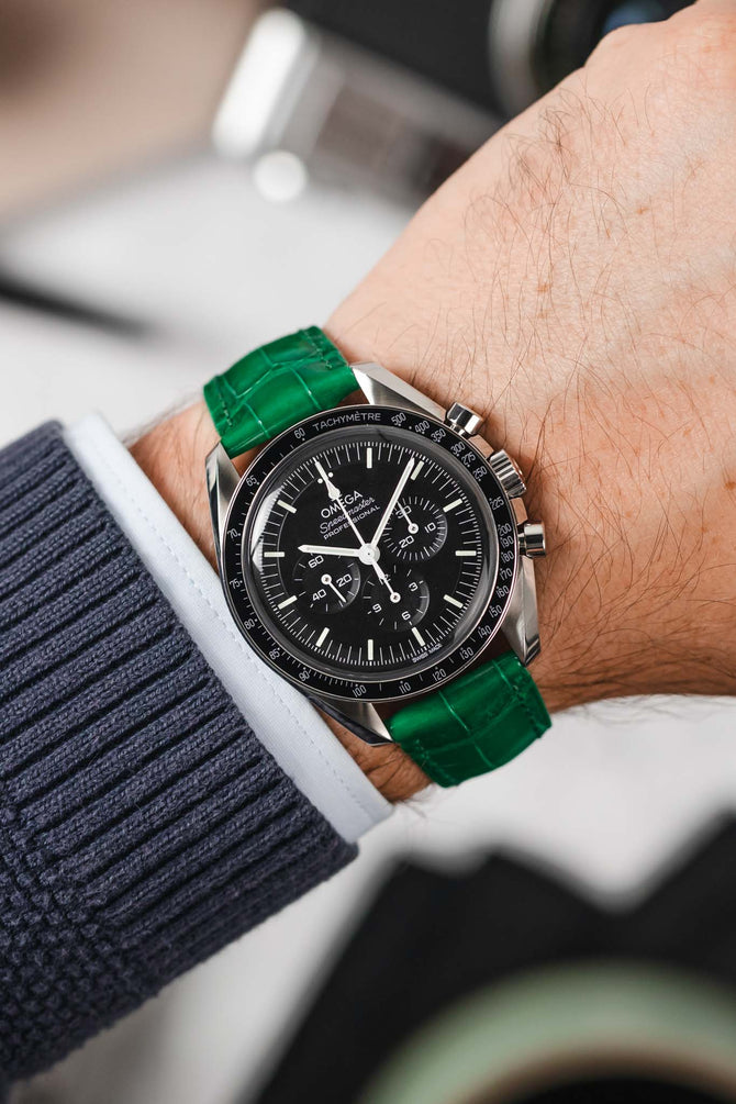 Black Omega Speedmaster Moonwatch fitted with Hirsch London green leather watch strap worn on wrist