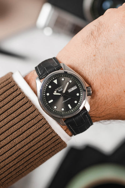 Grey Seiko 5 Sports SRPE55 fitted with Hirsch London grey alligator leather watch strap worn on wrist