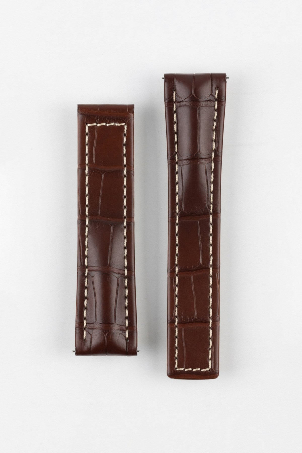 Brown leather watch strap displayed in two pieces on a light gray background. The strap features an embossed alligator-style pattern, cream contrast stitching, padded construction, and a smooth semi-gloss finish.