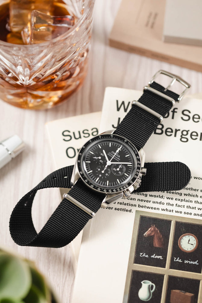 Military style watch strap with polished buckle on black Omega Speedmaster Professional