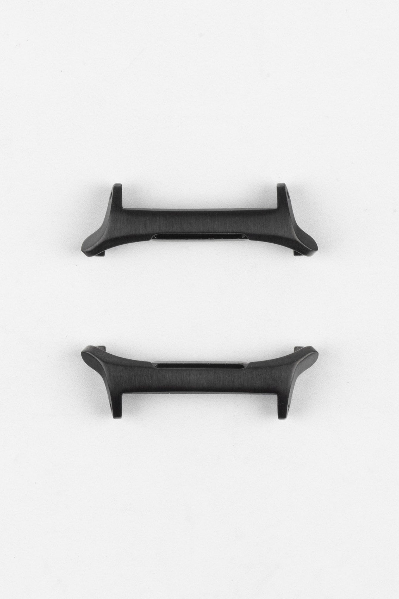 Two black smartwatch strap adapters with a matte finish, shown from different angles on a light grey background.