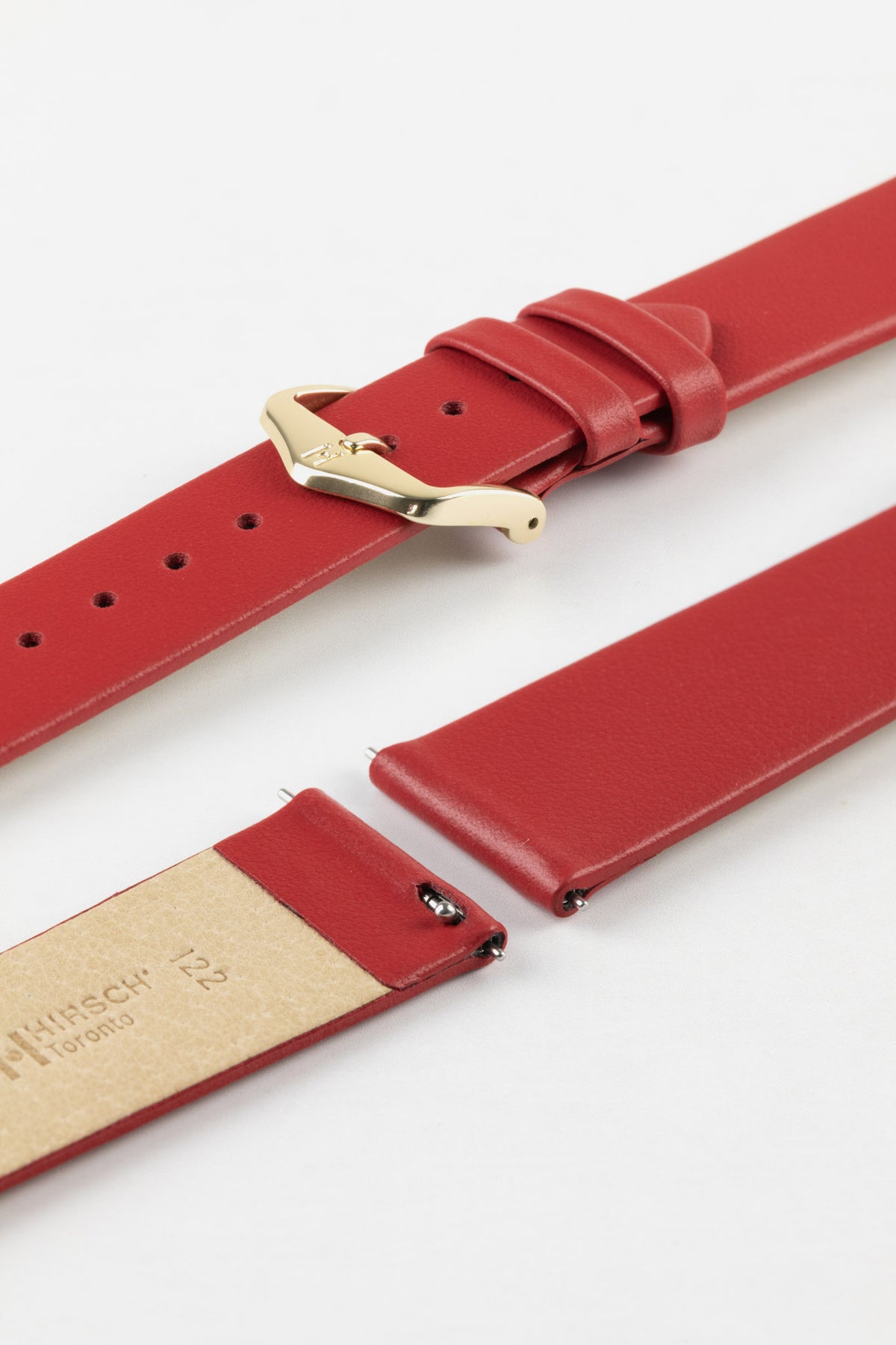 Close-up of a red leather watch strap displayed partially disassembled to showcase its integrated quick-release spring bars, smooth leather surface, matching red edge finishing, cream leather lining, and gold-tone pin buckle. The image highlights the strap’s premium craftsmanship, easy strap-change system, and classic styling against a clean white background.